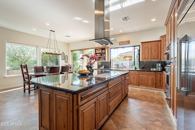 kitchen with hanging light fixtures, island range hood, a wealth of natural light, and a kitchen island