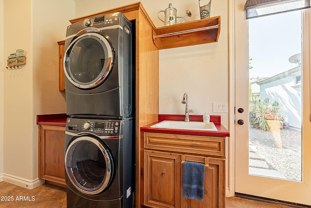 laundry room featuring cabinets, stacked washing maching and dryer, and sink