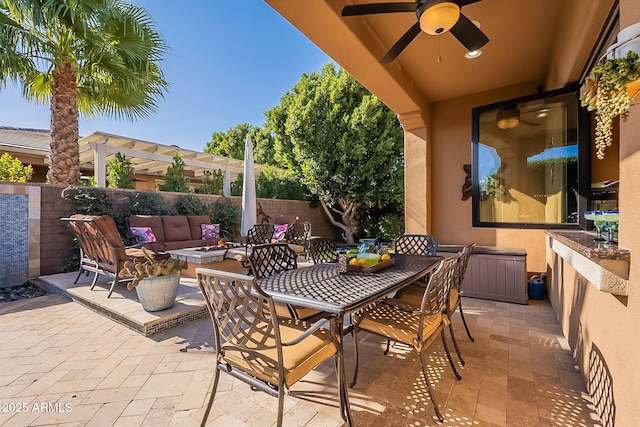 view of patio / terrace with ceiling fan and an outdoor living space with a fire pit