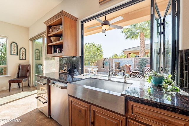 kitchen featuring dark stone countertops, sink, and ceiling fan