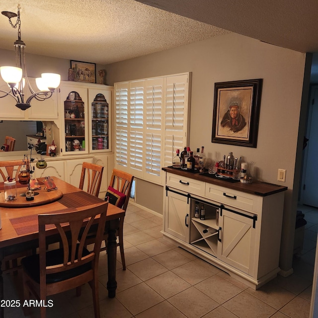 tiled dining space featuring an inviting chandelier and a textured ceiling