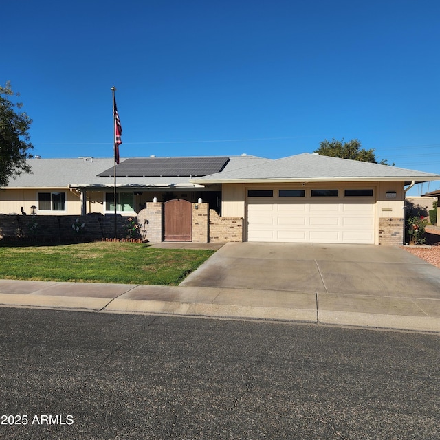 ranch-style house featuring a garage, a front yard, and solar panels