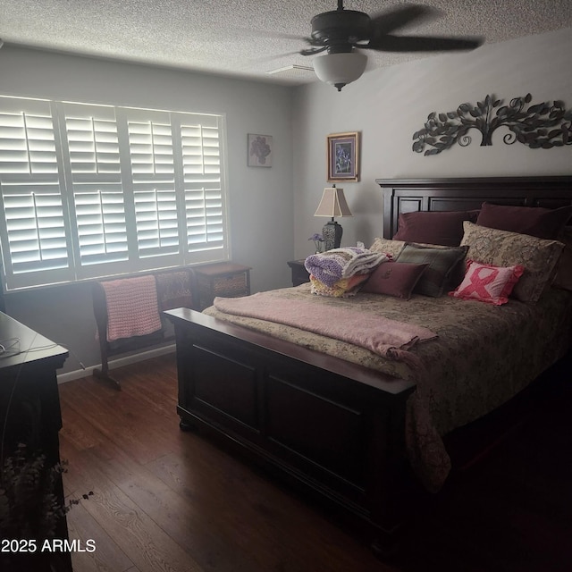 bedroom with dark wood-type flooring, a textured ceiling, and ceiling fan