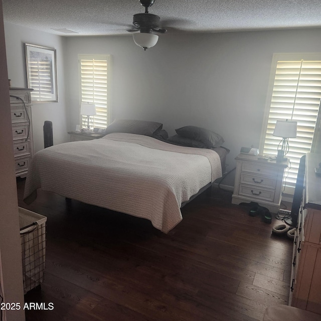 bedroom with dark wood-type flooring, ceiling fan, and a textured ceiling