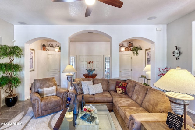 living room featuring ceiling fan, light tile patterned floors, and a textured ceiling