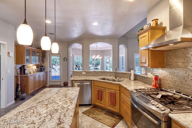 kitchen featuring pendant lighting, wall chimney range hood, appliances with stainless steel finishes, and a chandelier