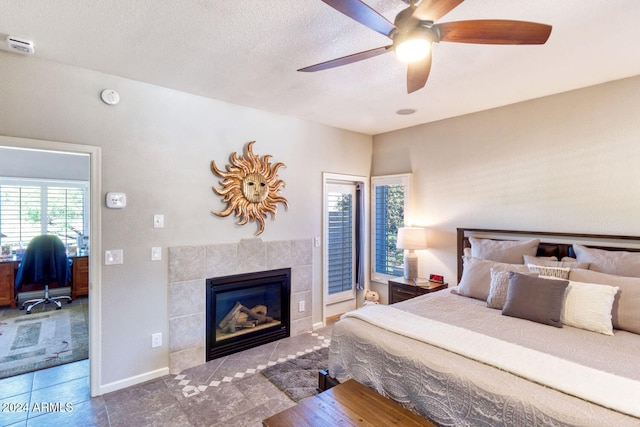 bedroom featuring ceiling fan, a fireplace, a textured ceiling, and tile patterned flooring