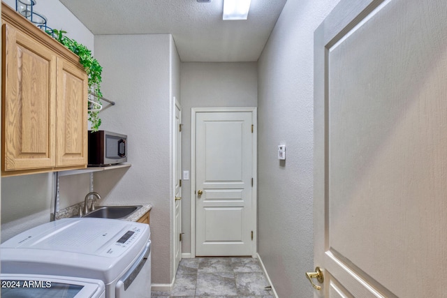 laundry room with a textured ceiling, cabinets, sink, and washing machine and dryer