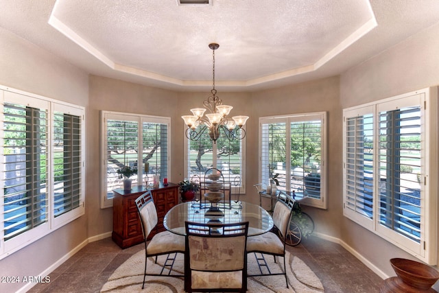 dining space featuring a raised ceiling, plenty of natural light, and a notable chandelier