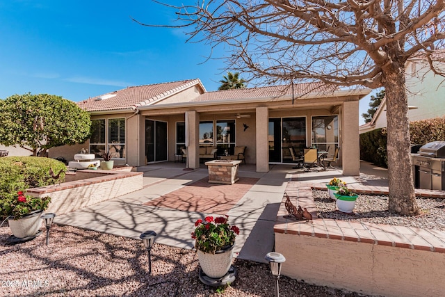 back of property with a ceiling fan, a tile roof, a patio, and stucco siding