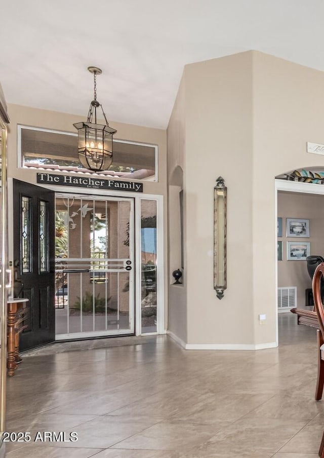 foyer with baseboards, visible vents, and a notable chandelier