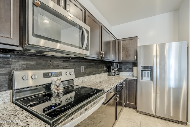 kitchen featuring light stone counters, light tile patterned flooring, dark brown cabinets, appliances with stainless steel finishes, and tasteful backsplash