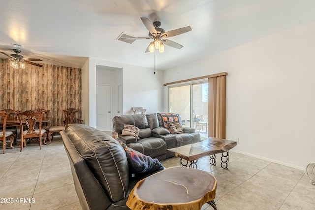 living room featuring light tile patterned floors, wooden walls, and a ceiling fan