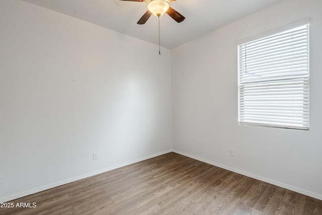 empty room with ceiling fan, wood finished floors, and baseboards