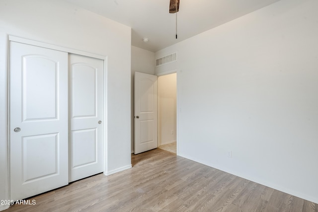 unfurnished bedroom with a closet, light wood-type flooring, and visible vents