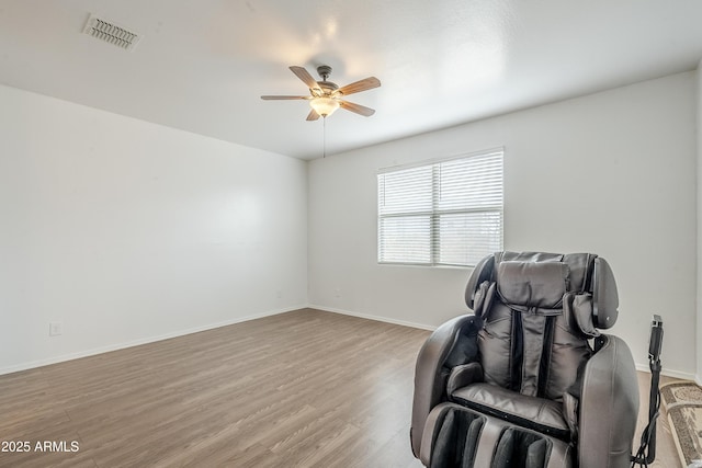 sitting room with light wood finished floors, ceiling fan, visible vents, and baseboards