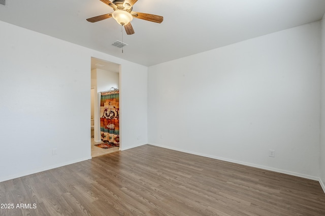 empty room featuring a ceiling fan, baseboards, visible vents, and wood finished floors