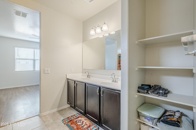 full bath with double vanity, a sink, visible vents, and baseboards