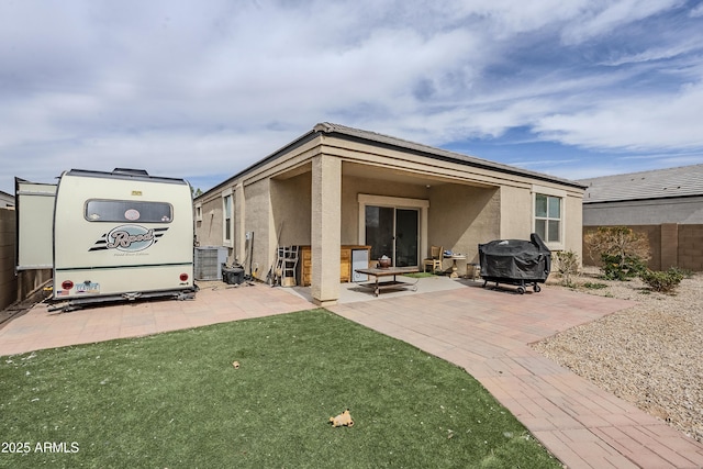 rear view of property with a patio area, a yard, fence, and stucco siding