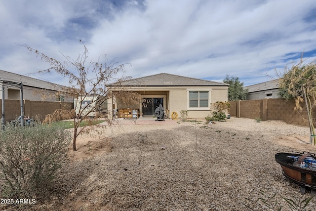 rear view of house with a tile roof, a patio area, a fenced backyard, and stucco siding