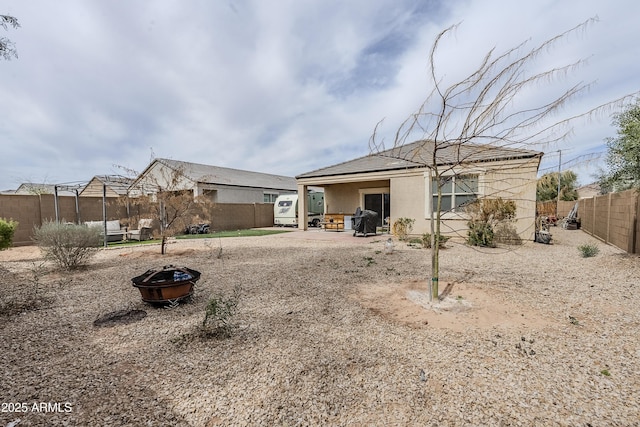 back of house with a patio area, an outdoor fire pit, a fenced backyard, and stucco siding