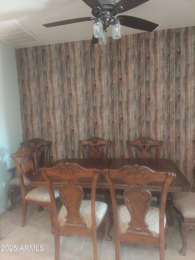 dining space featuring wood walls, visible vents, and a ceiling fan