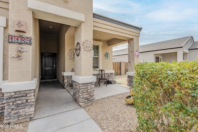 view of exterior entry with stone siding and stucco siding