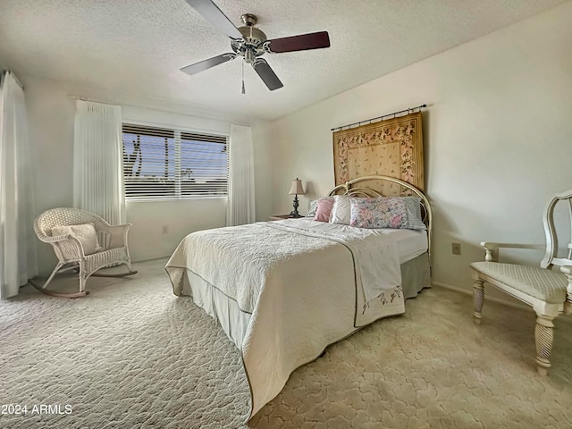 bedroom featuring a textured ceiling, light colored carpet, and ceiling fan