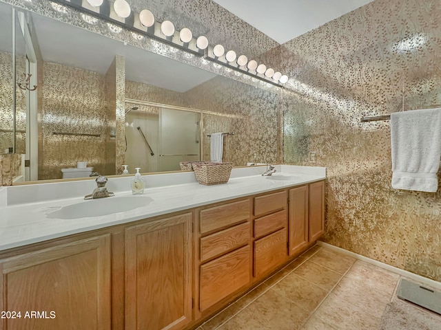 bathroom featuring tile patterned flooring, vanity, toilet, and a shower with shower door