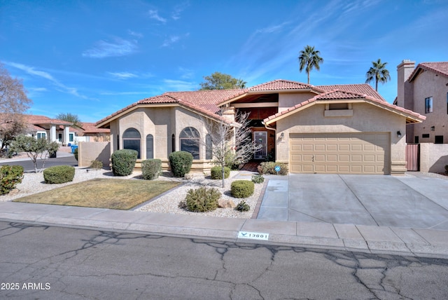 mediterranean / spanish-style home with concrete driveway, a tile roof, an attached garage, and stucco siding