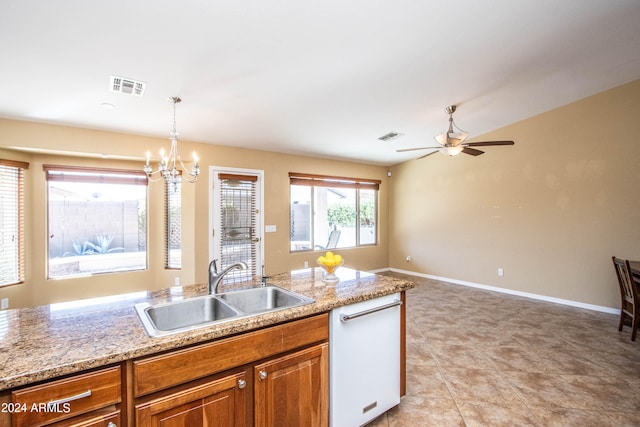 kitchen featuring light stone counters, ceiling fan with notable chandelier, white dishwasher, sink, and pendant lighting