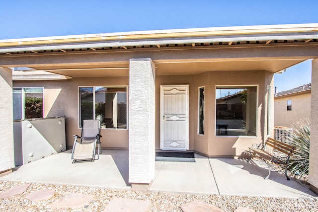 view of exterior entry with a patio and central AC unit