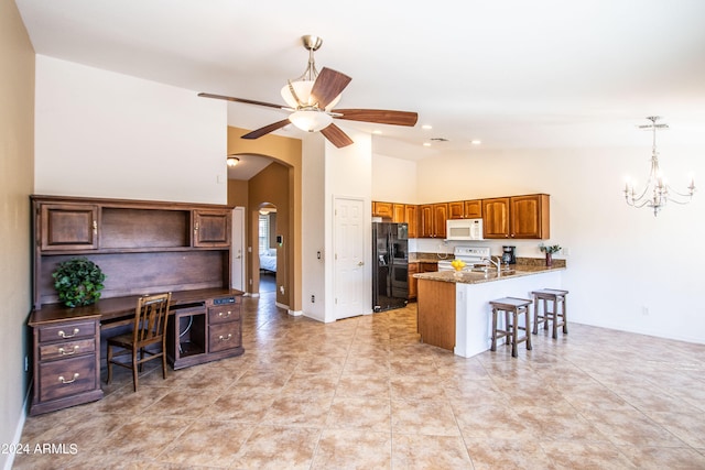 kitchen featuring white appliances, ceiling fan with notable chandelier, sink, kitchen peninsula, and a breakfast bar area