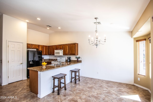 kitchen with kitchen peninsula, electric range, decorative light fixtures, a notable chandelier, and dark stone countertops