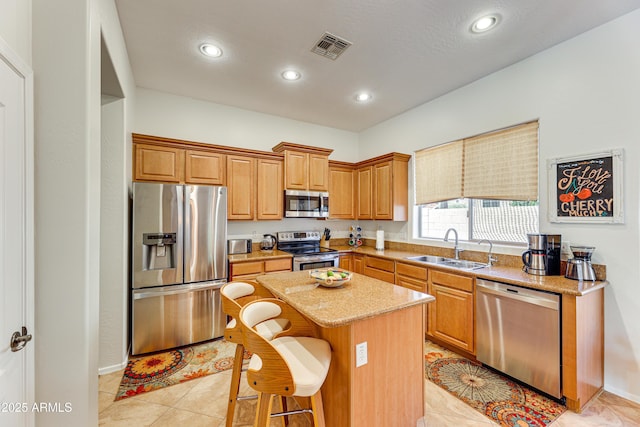 kitchen featuring a breakfast bar, sink, a center island, stainless steel appliances, and light stone countertops