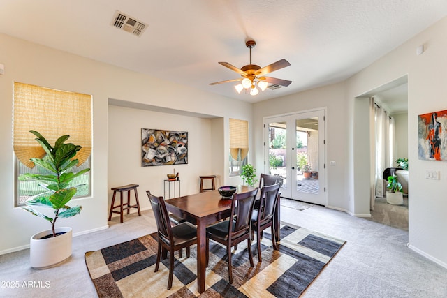 dining space featuring french doors, light colored carpet, and ceiling fan