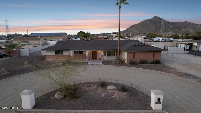 ranch-style house with a gate, fence, driveway, and a mountain view