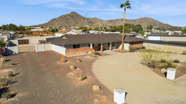 single story home with a mountain view, dirt driveway, and fence