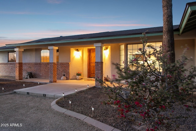 entrance to property featuring brick siding and stucco siding