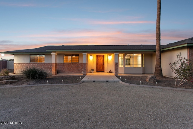 view of front of property featuring brick siding and stucco siding