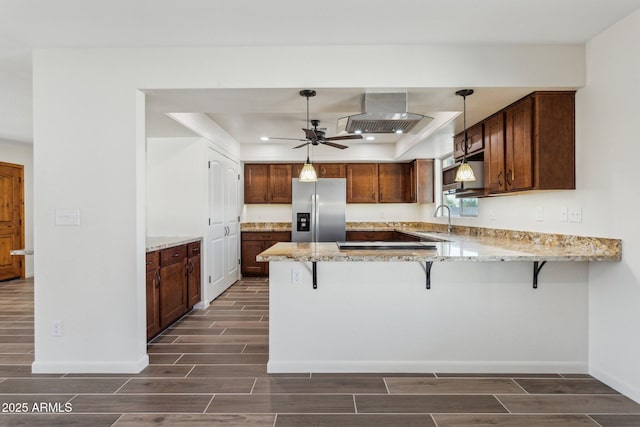 kitchen with wood finish floors, a sink, stainless steel fridge, a peninsula, and extractor fan