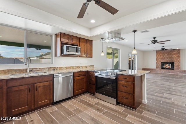 kitchen featuring visible vents, a peninsula, stainless steel appliances, wood finish floors, and a sink