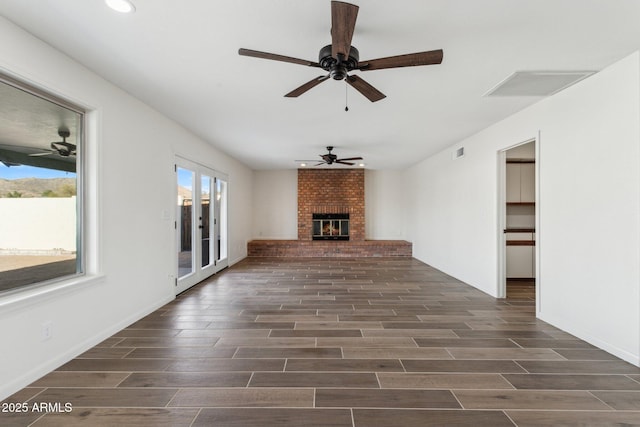 unfurnished living room featuring wood finish floors, a brick fireplace, and visible vents