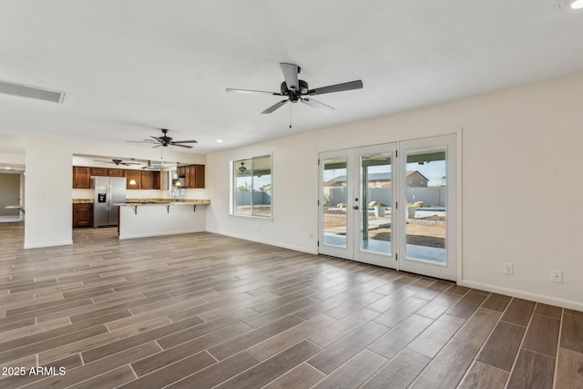 unfurnished living room with wood tiled floor, visible vents, baseboards, and ceiling fan