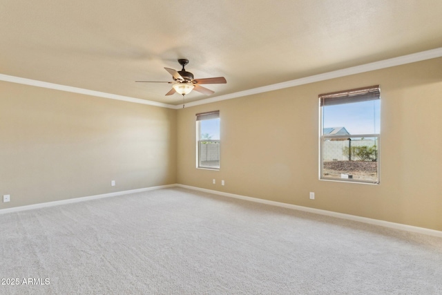 spare room with ceiling fan, baseboards, crown molding, and light colored carpet