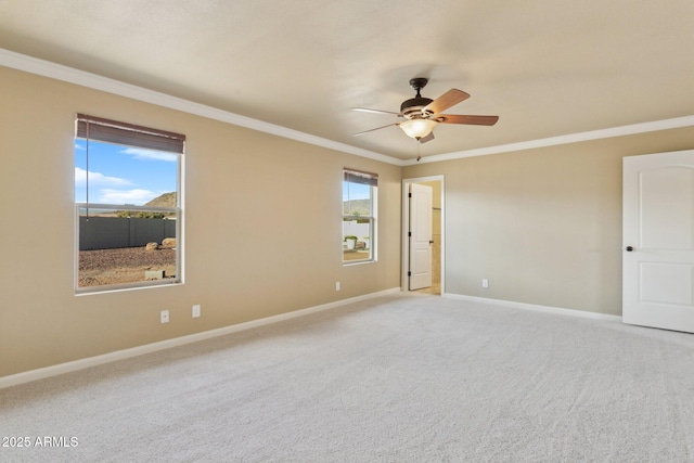 empty room featuring ornamental molding, carpet flooring, baseboards, and a ceiling fan