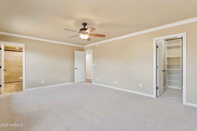 unfurnished bedroom featuring carpet floors, a walk in closet, crown molding, and baseboards