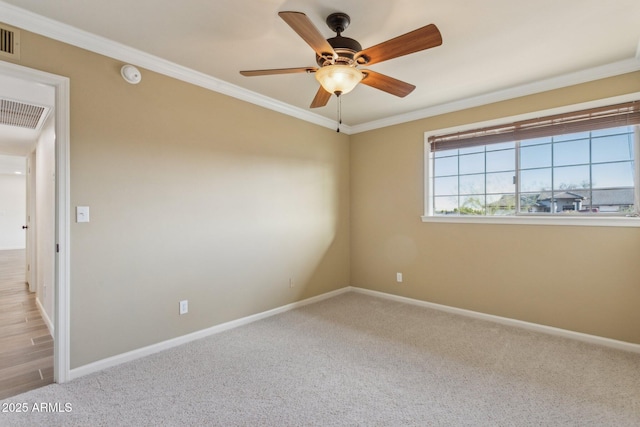 carpeted spare room with a ceiling fan, baseboards, visible vents, and crown molding