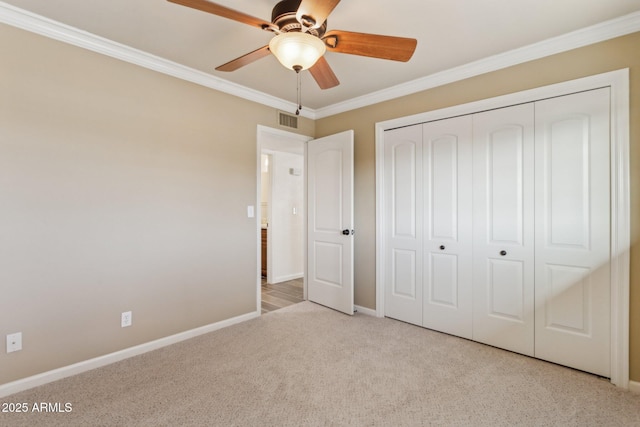 unfurnished bedroom with baseboards, visible vents, crown molding, carpet floors, and a closet