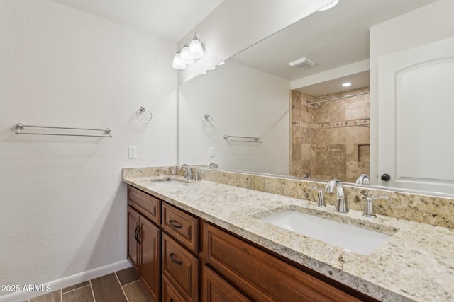 bathroom featuring wood finish floors, a sink, baseboards, and double vanity